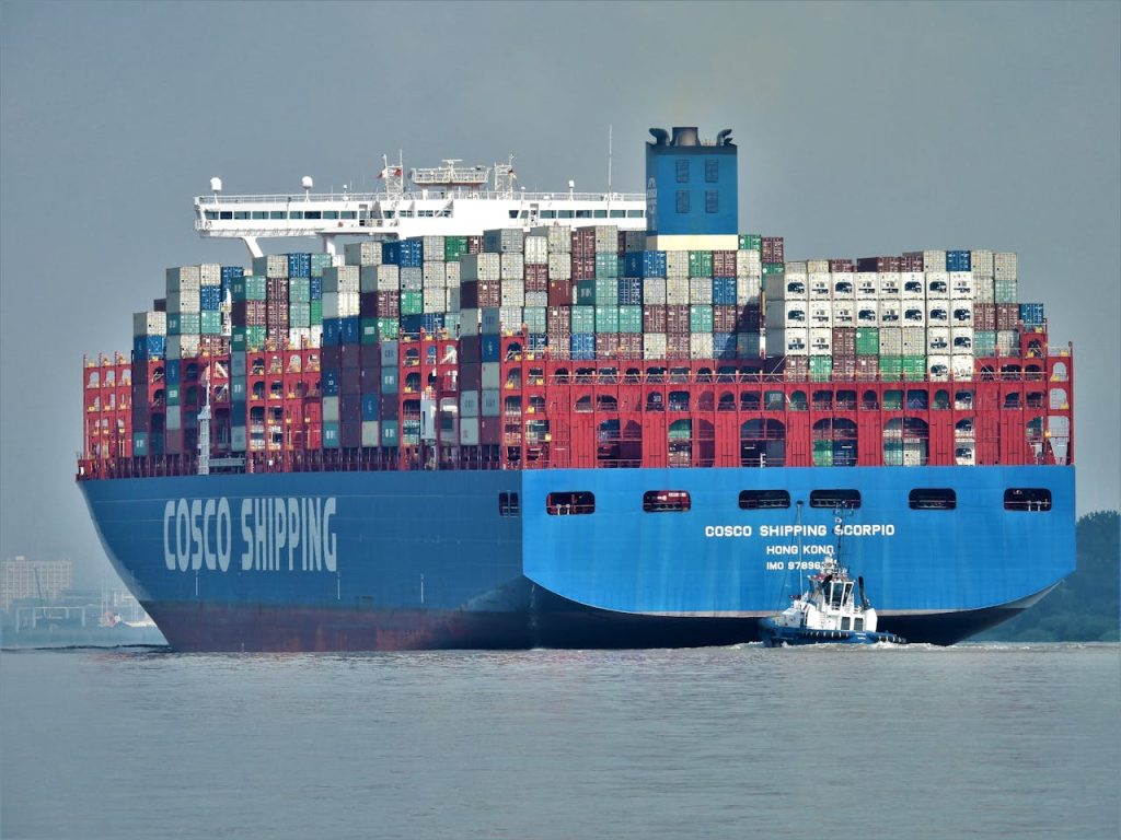 Large cargo ship navigating through Hamburgs waters, laden with shipping containers.